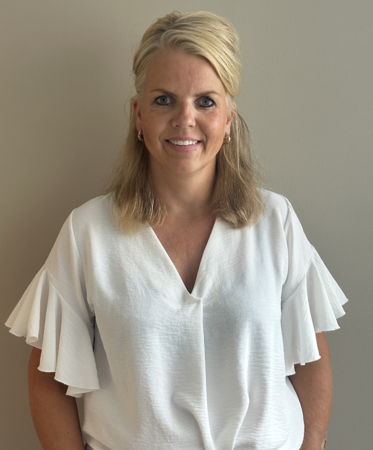 Glimlachende vrouw met blond haar in een witte blouse