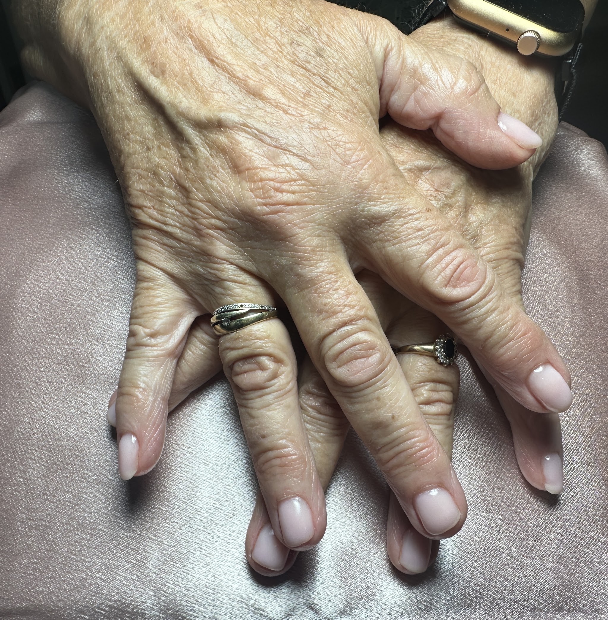 Twee handen met zachte nude nagels op een satijnen doek