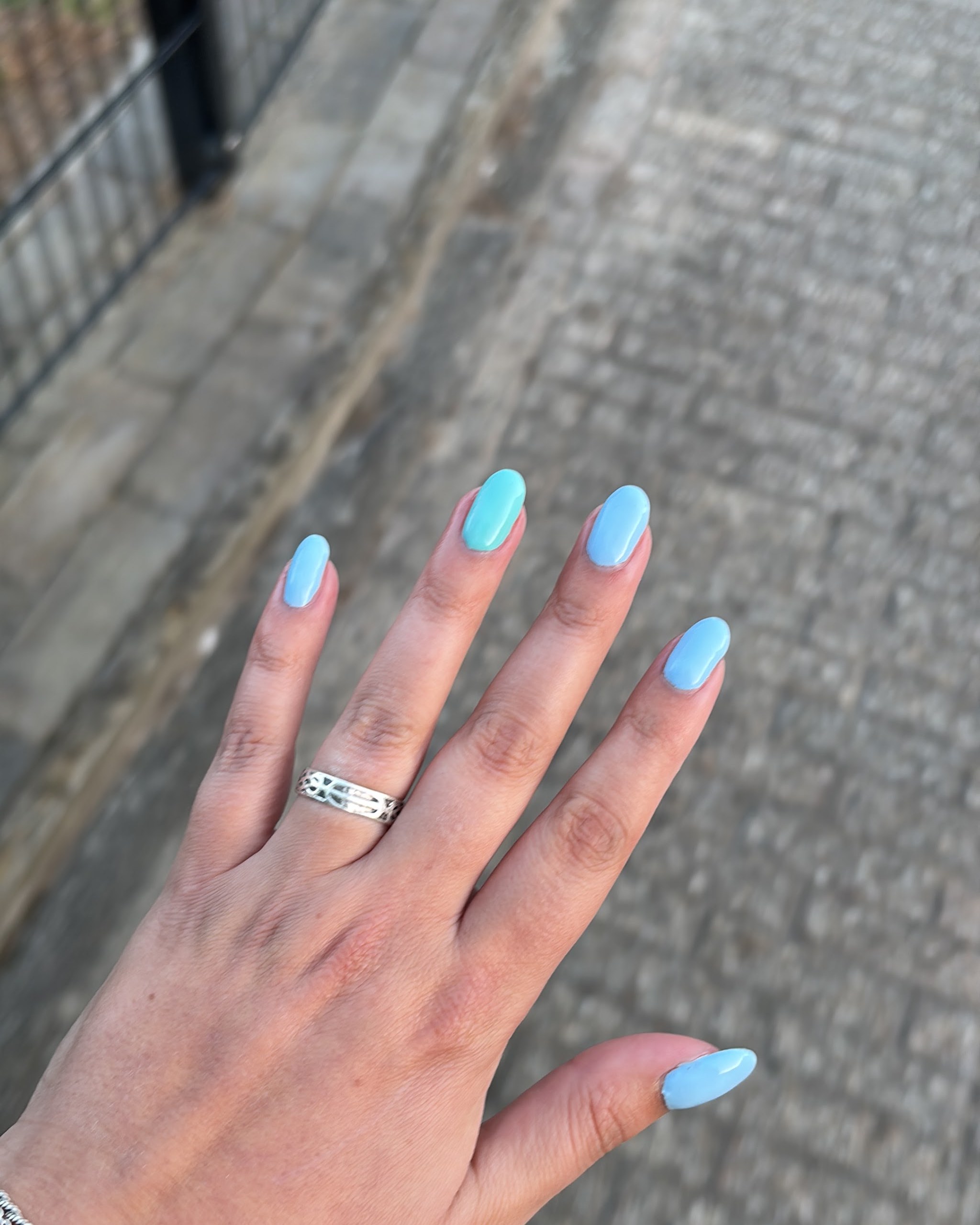 Hand met ijsblauwe amandelnagels en een zilveren ring